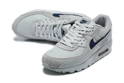 Top view of grey and navy Nike Air Max 90 sneakers with lace-up fronts.