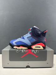 Profile view of one blue and navy high-top sneaker with red accents and a cream-colored outsole.