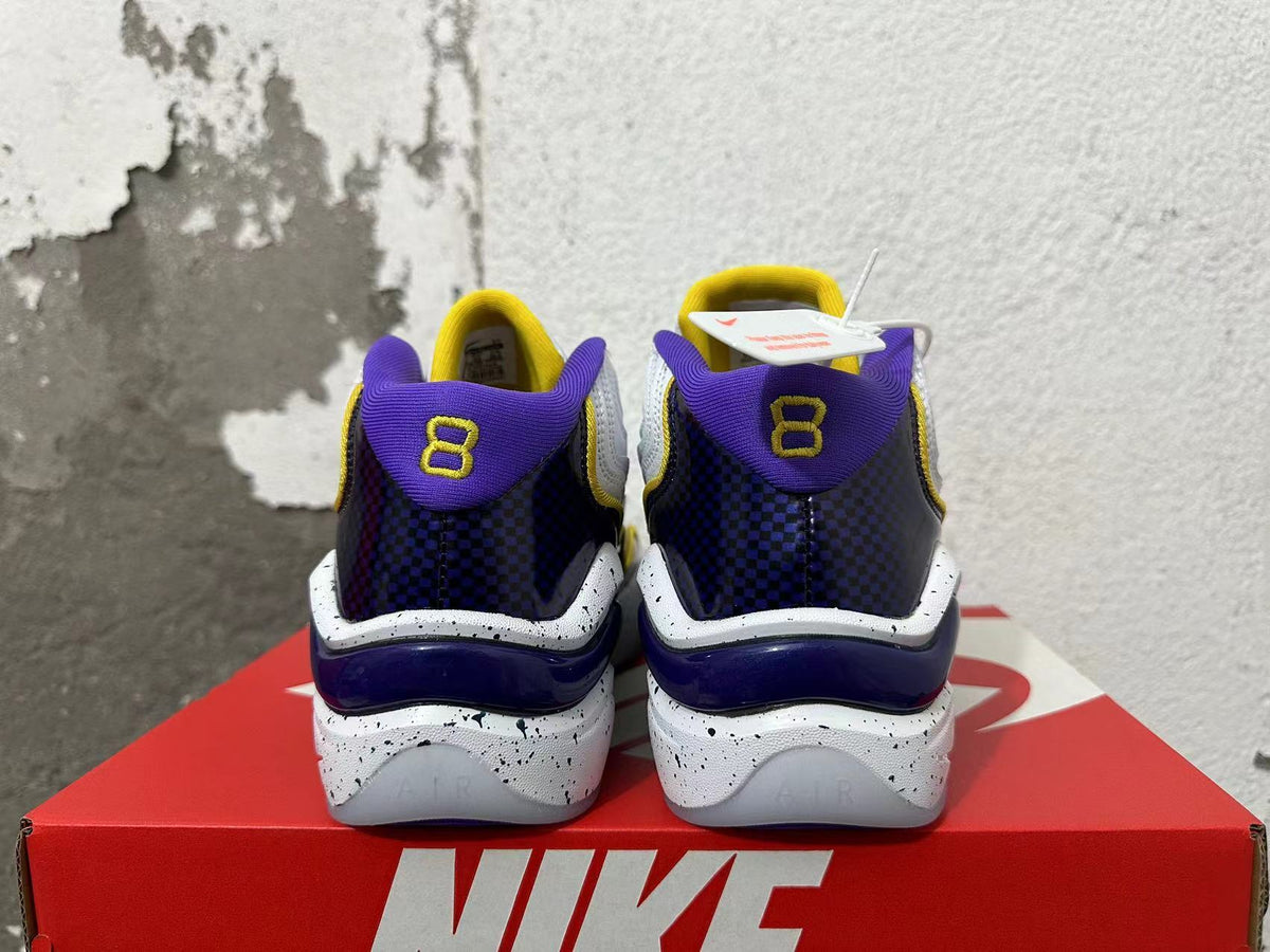 Rear view of white Nike sneakers with purple heel panels, yellow accents, and speckled midsoles.