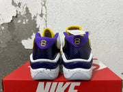 Rear view of white Nike sneakers with purple heel panels, yellow accents, and speckled midsoles.