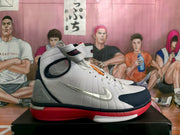 Side profile of a white high-top sneaker with a navy toe panel, red outsole, ankle strap, and metallic Swoosh.