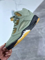Close side view showing the green upper, mesh panel, black midsole, heel window, and gum-colored outsole.