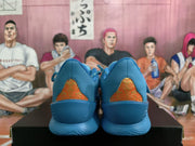 Rear view of blue sneakers showing orange-and-gold patterned heel panels and textured blue outsoles.