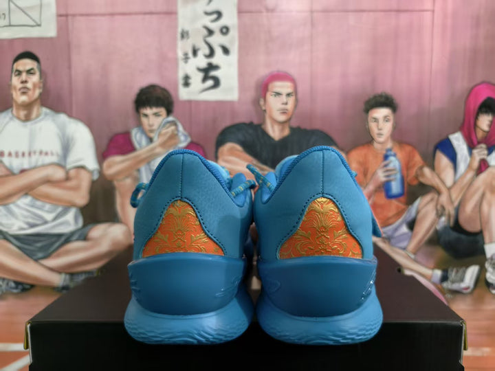 Rear view of blue sneakers showing orange-and-gold patterned heel panels and textured blue outsoles.