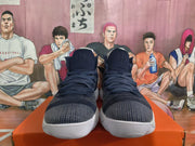 Front view of navy high-top basketball shoes with lace-up closures and knit-patterned uppers.