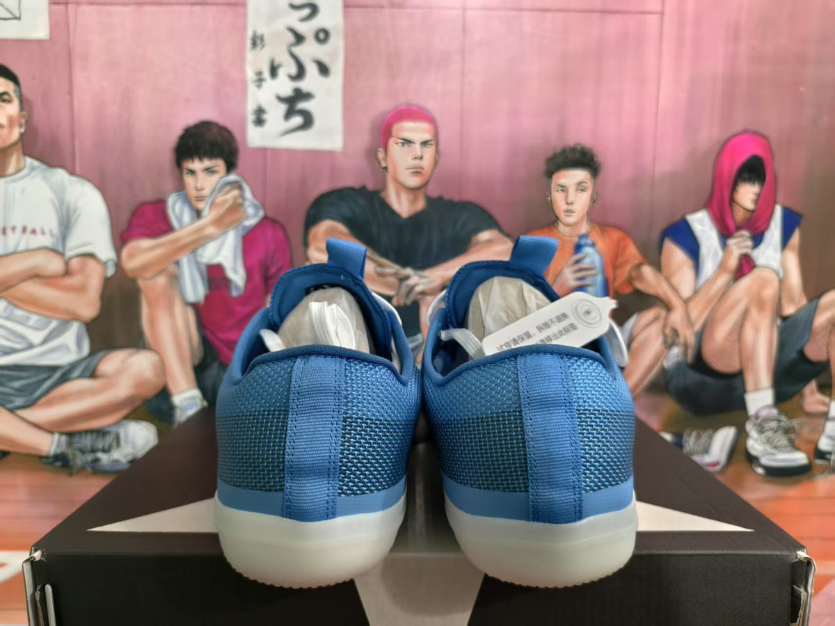 Rear view of blue low-top sneakers with padded collars and light-colored soles on a shoe box.