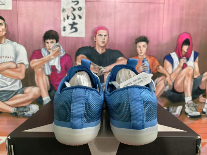 Rear view of blue low-top sneakers with padded collars and light-colored soles on a shoe box.