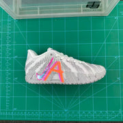 Side view of a white and gray Nike basketball shoe with bright orange and pink accents