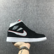 Side profile of a black mid-top Jordan sneaker with silver branding, red edging, white midsole and gray outsole.