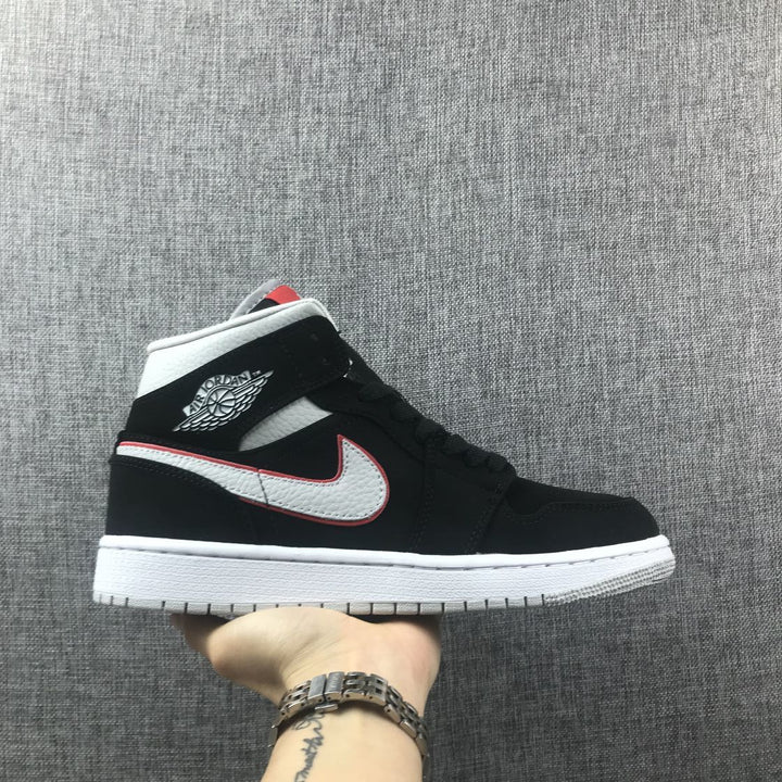 Side profile of a black mid-top Jordan sneaker with silver branding, red edging, white midsole and gray outsole.