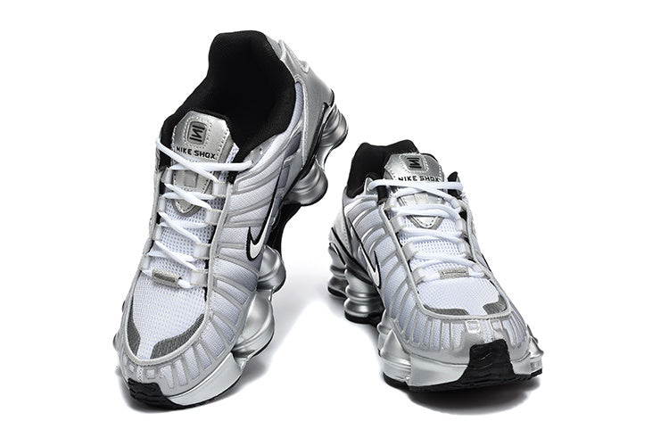 Pair of silver Nike Shox TL sneakers viewed from the front, showing the laces and column-shaped soles.