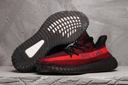 Red and black knit sneaker shown in side profile with the outsole of a second shoe visible above it.