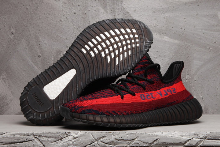 Red and black knit sneaker shown in side profile with the outsole of a second shoe visible above it.