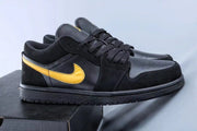 Pair of black low-top Jordan sneakers with yellow side branding and black rubber soles.
