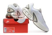 White and grey Nike Air Max DN sneakers displayed with a Nike shoe box and size label.