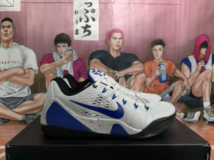 White and blue Nike basketball sneaker shown in side profile with blue Swoosh branding, perforated panels and a speckled midsole.