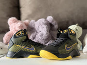 Three-quarter view of the black and yellow high-top sneakers with purple Swoosh detailing.