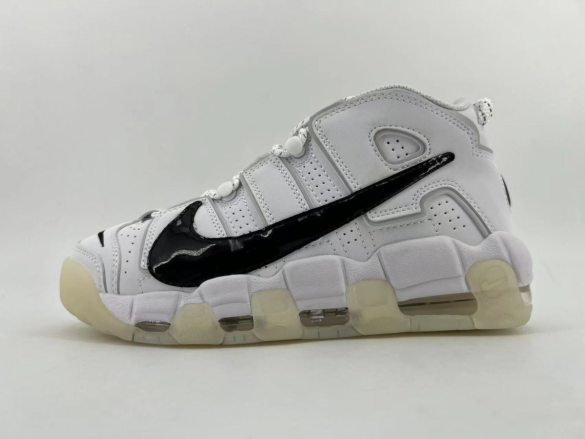 Side view of a white Nike Air More Uptempo sneaker with a large black swoosh and segmented sole.
