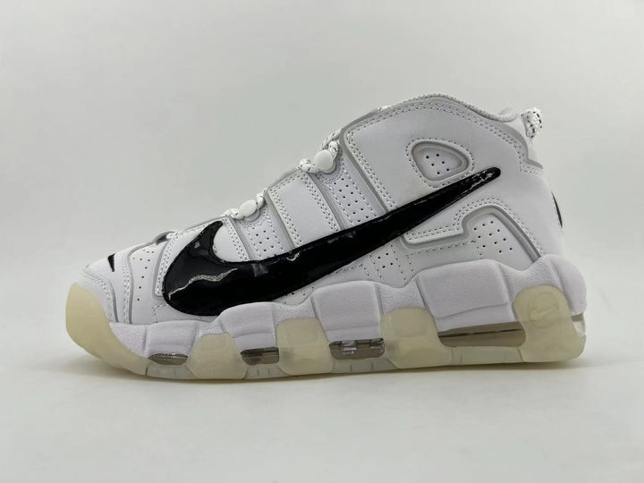Side view of a white Nike Air More Uptempo sneaker with a large black swoosh and segmented sole.