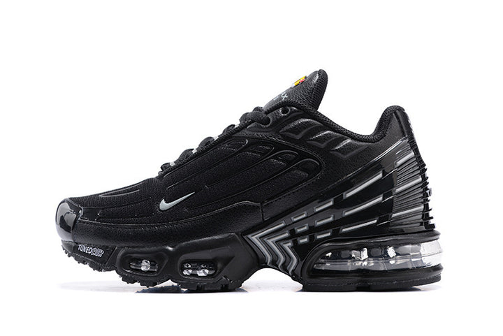 Side view of a black Nike Air Max Plus sneaker with visible cushioning units and sculpted heel detailing