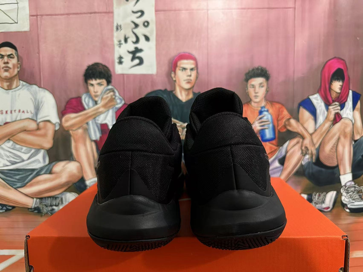 Rear view of a pair of all-black Nike basketball shoes on an orange box.