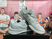Gray and white Nike basketball sneakers shown at an angled front-side view, highlighting the laces, side branding, padded collar, and outsole.