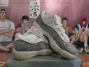 Angled view of the pair on a box, highlighting the patterned gray panels, white uppers, and translucent-tinted outsoles.
