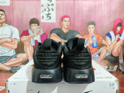 Rear view of black Nike sneakers showing padded heel panels, pull tabs, and Nike heel branding.