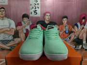 Front view of mint green Nike sneakers showing matching laces, red collar accents, and white textured soles.