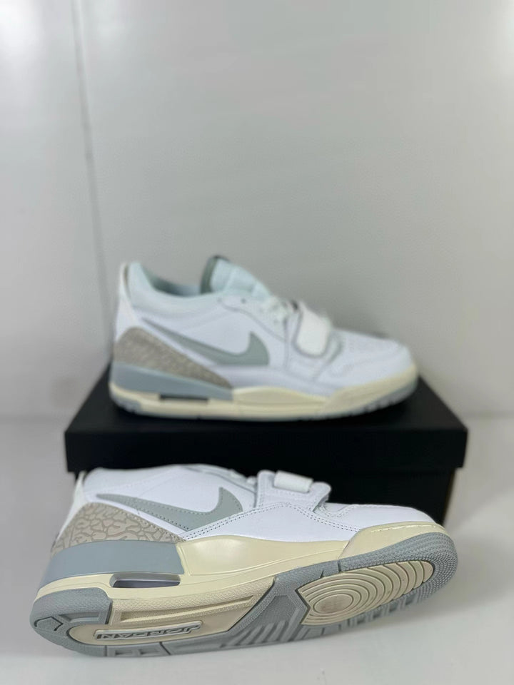 Pair of white and silver Jordan Legacy 312 Low sneakers with yellowed midsole accents, shown from side and outsole angles.