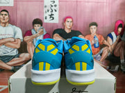 Rear view of the blue and yellow sneakers showing striped heel panels, signature-style graphics, and white midsoles.