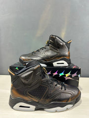 Angled side view showing the black perforated upper, bronze-toned detailing, and contrasting midsole.