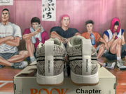 Rear view of gray patterned Nike Book 1 sneakers with white heel tabs and gum-colored outsoles, displayed on a shoe box.