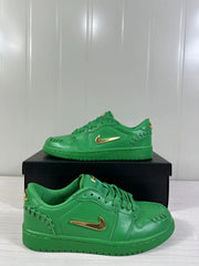Angled side view of green low-top sneakers with metallic gold Swoosh details and stitched panels.