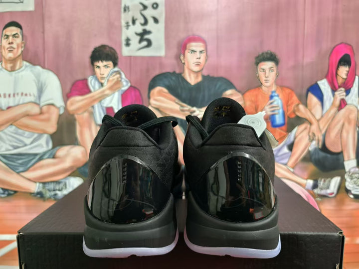 Rear view of black and dark purple Nike basketball sneakers with glossy heel panels and translucent outsoles.