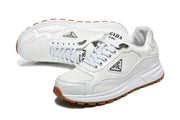 White Prada lace-up sneakers with layered panels and triangular side logo plaques.