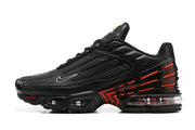 Side profile of a black Nike Air Max Plus sneaker with red detailing
