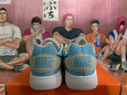 Rear view of blue and white Nike sneakers showing the heel branding and ribbed white outsoles.