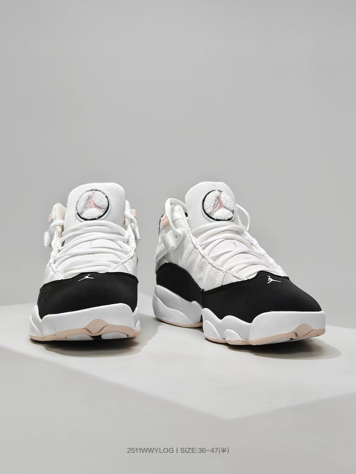 Front view of white and black Jordan high-top sneakers with pink accents and Jumpman tongue logos.