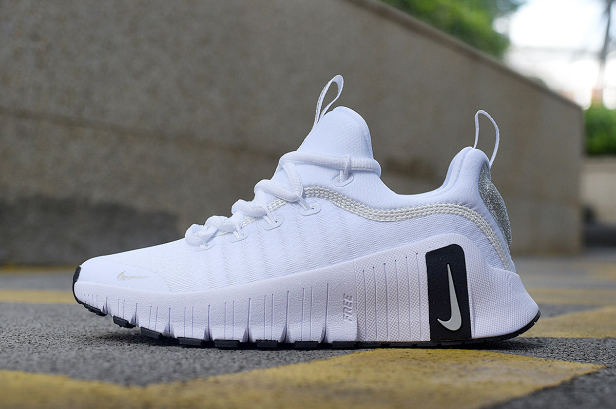 White Nike low-top lace-up sneaker with black heel and outsole accents, shown from the side.