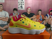 Side profile of a yellow sneaker showing orange side detailing, green dot graphics, red collar trim, and a white textured sole.