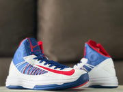 Front three-quarter view of the white, blue, and red high-top sneakers.