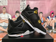 Angled view of black basketball-style sneakers showing mesh panels, gold-toned hardware, and visible air units.