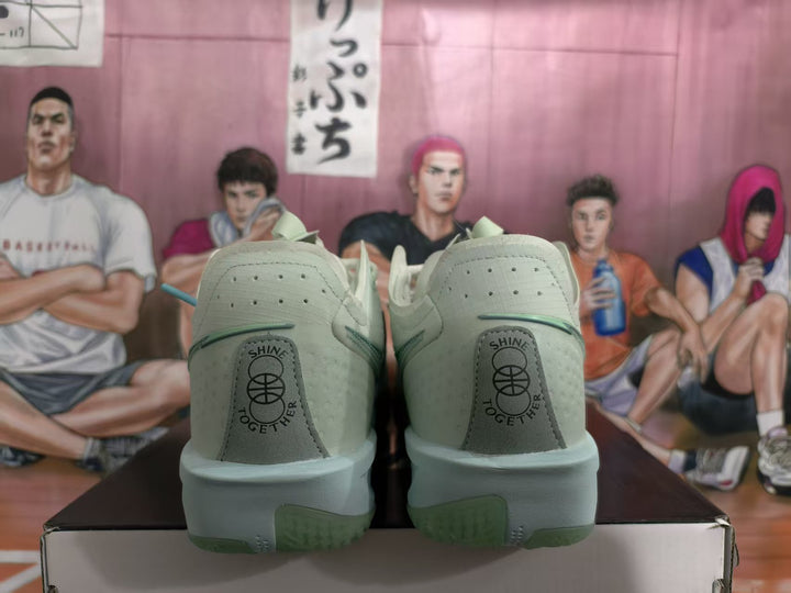 Rear view of green Nike basketball sneakers showing heel text, contrasting green outsole details, and the shoes resting on a box.