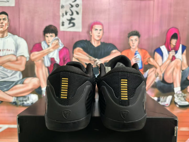 Rear view of black basketball sneakers showing gold heel details and Kobe logos.