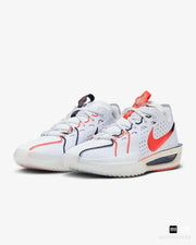 White Nike basketball sneakers with orange-red Swooshes, navy detailing, and contrasting outsole accents.