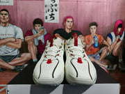 Front view of the white basketball sneakers showing perforated uppers, white laces, red tongue details, and black trim.