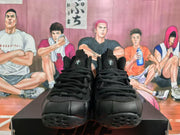 Front view of black Nike sneakers showing tonal laces, rounded toe boxes, textured tongues, and molded outsoles.