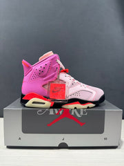 Side profile of a pink and white Jordan high-top sneaker with red and black accents displayed on its box.