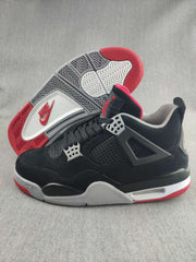 Side view of a black sneaker with a red-and-gray rubber outsole shown behind it.